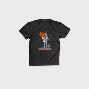 May include: Black t-shirt with a cartoon illustration of a baseball player wearing a blue and white baseball cap with the letter "B" on it. The player is holding a baseball bat and has red hair.