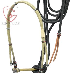 Puede incluir: Un cabezada de cuerda trenzada con una bozal de cuerda trenzada blanco y negro y una cuerda de plomo negra. La cabezada está hecha de cuerda de color natural con acentos rojos y negros.