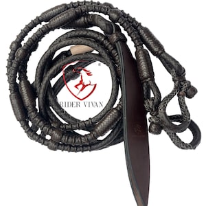 May include: A brown leather horse riding rein with a braided design and a leather strap. The rein has a knotted end and a loop for attaching to a bit.