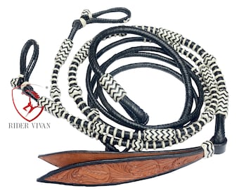 Könnte beinhalten: Schwarze und weiße geflochtene Leder-Pferdezügel mit einem braunen Leder-Endstück. Die Zügel haben ein Zickzackmuster und weiße Perlen.