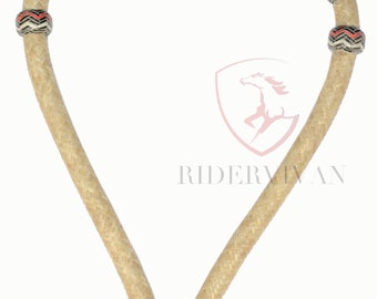 Può includere: Un capezza per cavalli in tonalità naturali, con un motivo decorativo nero, bianco e rosso. Il capezza presenta un design intrecciato sulle sezioni superiore e inferiore, con un nodo decorativo rotondo alla base. Il testo "RIDERVIVAN" è visibile.