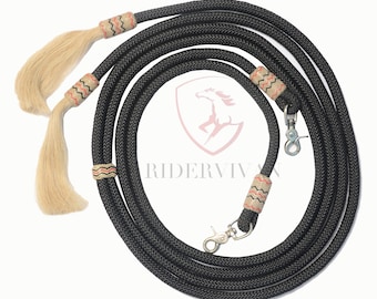 Könnte beinhalten: Schwarze geflochtene Leder-Pferdezügel mit zwei Quasten und dekorativen Nähten. Die Zügel haben silberne Karabinerhaken.