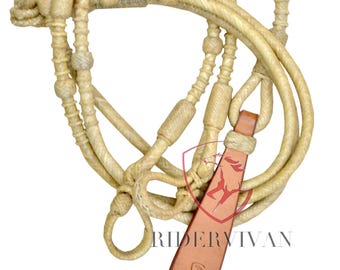 Könnte beinhalten: Ein weißes Leder-Pferde-Zügel mit einem braunen Leder-Endstück. Das Zügel hat ein geflochtenes Design und ist mit kleinen, runden Perlen verziert. Das Endstück hat den Text "RIDERVIVAN" geprägt.