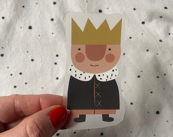 May include: A sticker of a cartoon king wearing a gold crown and a black coat with white trim. The king has a brown nose and rosy cheeks.