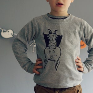 May include: A grey sweatshirt with a black and white illustration of a bat hanging upside down. The bat has a smiling face and a small nose.