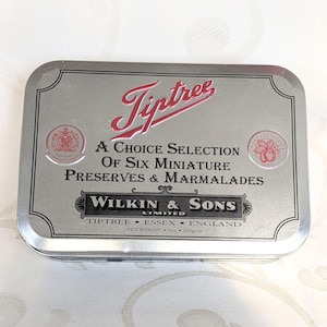 Può includere: Una scatola rettangolare argentata con il logo Tiptree in rosso. La scatola recita "A Choice Selection of Six Miniature Preserves & Marmalades" e "Wilkin & Sons Limited". Peso netto: 250g.