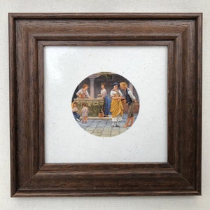 Könnte beinhalten: Ein gerahmtes Gemälde, das eine Gruppe von Menschen zeigt, die um einen Brunnen in einem Innenhof stehen. Das Gemälde ist in einem braunen Rahmen und hat einen weißen Passepartout.