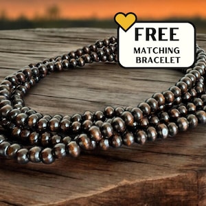 May include: A dark brown wooden bead necklace with multiple strands. The necklace is on a wooden surface. Free matching bracelet included.