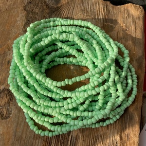 Puede incluir: Una larga hebra de cuentas de vidrio verde claro, perfecta para hacer joyas o agregar un toque de color a la decoración de tu hogar.