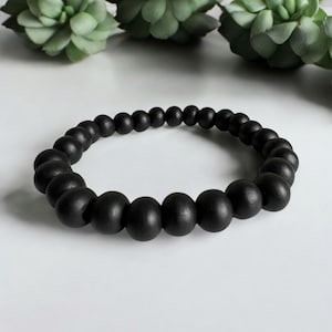 May include: A black beaded bracelet with round beads. The bracelet is made of matte black beads.