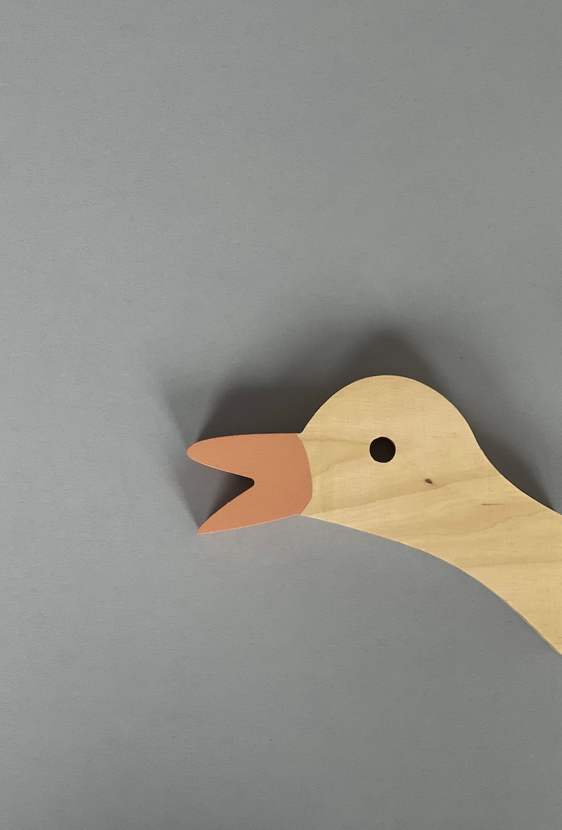 Op de afbeelding: Een houten ganzenkop met een lichtbruin lichaam en een roze snavel. De gans heeft een klein zwart oog.