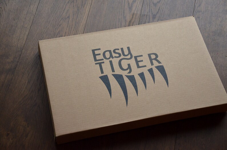 May include: A brown cardboard box with the words "Easy Tiger" printed in black on the top. The logo also includes a stylized black tiger claw print.