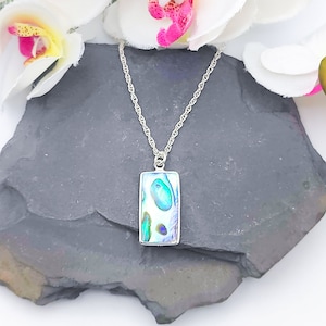 May include: A silver chain necklace with a rectangular abalone shell pendant. The pendant has a blue, green, and white iridescent pattern.