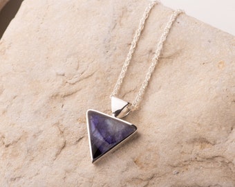 May include: A silver chain necklace with a triangular pendant featuring a purple and blue gemstone.