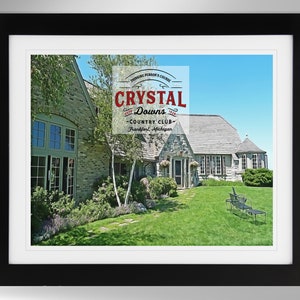 May include: A framed print of a stone house with a green lawn and a blue sky. The house has a sign that says "Crystal Downs Country Club - Frankfort, Michigan".