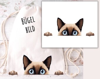May include: A white canvas tote bag with the text "Bügel Bild" printed on it. A Siamese cat peeks over the top of the bag with its paws on either side.