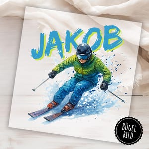 May include: Watercolor illustration of a skier in action, wearing a green and blue ski suit and helmet. The name "JAKOB" is written in blue and green above the skier. The image is on a white background with a black and white circular logo in the bottom right corner.