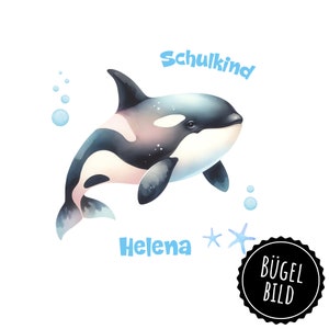 Könnte beinhalten: Ein schwarz-weißes Orca-Wal mit blauem Hintergrund. Der Text "Schulkind" befindet sich über dem Wal und der Text "Helena" unter dem Wal. Es gibt zwei blaue Seesterne und einen blauen Kreis mit dem Text "Bügel Bild" in Schwarz.