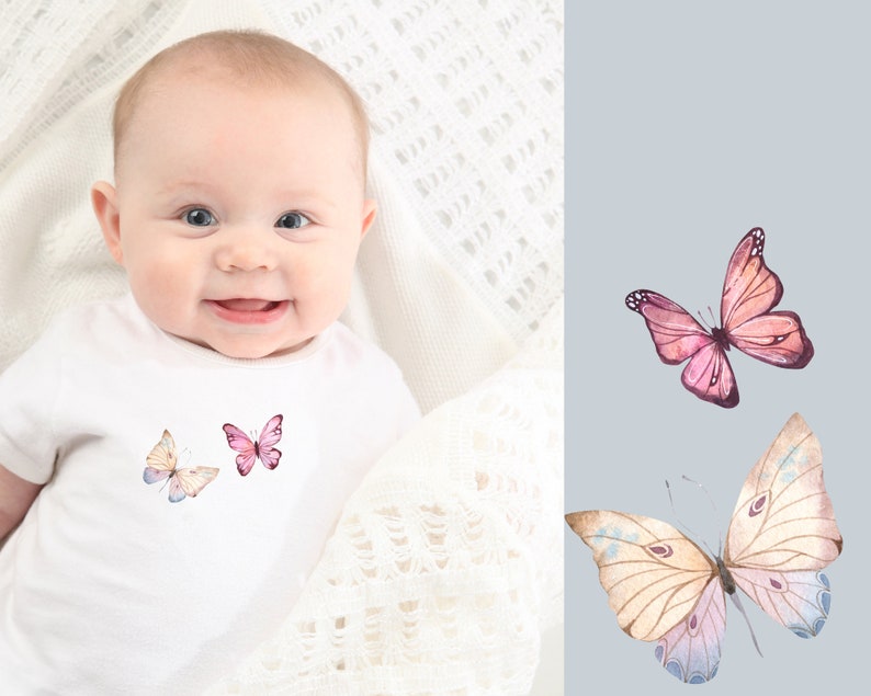 May include: A white onesie with a pink and white butterfly design. The onesie is worn by a baby with a happy expression.