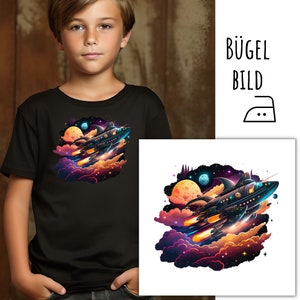 May include: Black t-shirt with a vibrant graphic of a spaceship flying through a nebula, with planets and stars. The design uses oranges, purples, and blues. The image also includes the text "BÜGEL BILD" and an iron symbol.