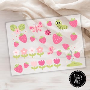 Könnte beinhalten: Bügelbilder mit verschiedenen Designs in Pink und Grün, darunter Erdbeeren, Blumen, Schmetterlinge, ein Marienkäfer und eine Raupe. Der Text "Bügel Bild" ist in der rechten unteren Ecke sichtbar.