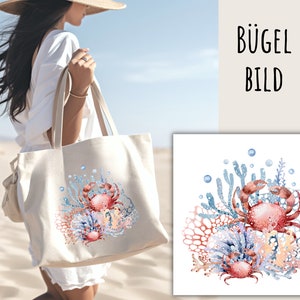 May include: A white tote bag featuring a design of two red crabs in a coral reef setting. The design is printed on the bag. The bag is being held by a person wearing a white dress and a straw hat.