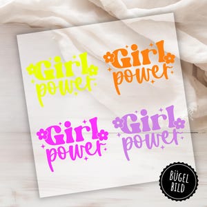 Könnte beinhalten: Vier Bügelbilder mit dem Text "Girl Power" in verschiedenen Farben: Gelb, Orange, Pink und Lila. Jedes Design hat eine stilisierte Schriftart und kleine Blumenakzente.