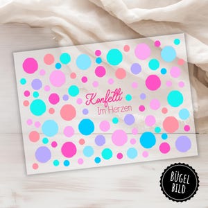 Peut inclure: Transfert thermocollant avec un fond blanc et des confettis colorés et le texte "Konfetti Im Herzen" en rose.