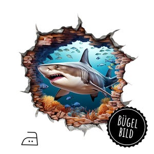 Può includere: Uno squalo bianco con la bocca aperta nuota attraverso un muro screpolato, rivelando una scena sottomarina blu con coralli e pesci. Il testo "BÜGEL BILD" è su un cerchio nero.