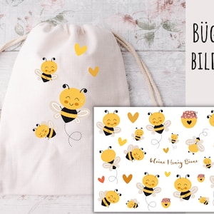May include: A white drawstring bag with a set of iron-on bee and honeycomb designs. The designs feature yellow and black bees with smiling faces and honeycombs with red and white polka dots. The text "Bügel Bilder" and "Kleine Honig Biene" are also included in the design.