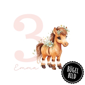 Op de afbeelding: Waterverfillustratie van een bruine pony met een bloemenkrans en accenten. Een groot roze cijfer 3 staat naast de pony, met de naam "Emma" in cursief. De afbeelding heeft een witte achtergrond en een zwarte cirkel met de tekst "BÜGEL BILD".