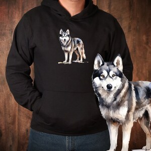 May include: A black hoodie with a watercolor illustration of a wolf on the front. The wolf is gray and white with a black nose and eyes. The hoodie has a drawstring hood and a kangaroo pocket.