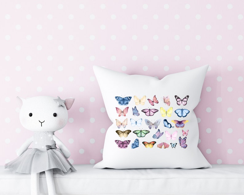 May include: White pillow with a colorful butterfly pattern. The butterflies are in various shades of pink, blue, yellow, and green. The pillow is on a pink background with white polka dots.