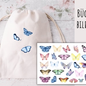 May include: A white drawstring bag with blue butterfly iron-on transfers. The bag is lying on a white wooden surface. A sheet of paper with colorful butterfly iron-on transfers is shown next to the bag. The paper has the text "B&uuml;gel Bilder" printed on it.
