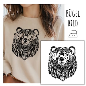 Peut inclure: Transfert thermocollant avec une illustration en noir et blanc d'un ours portant des lunettes de soleil en forme de cœur avec le texte "Mama Bear" sur les verres.
