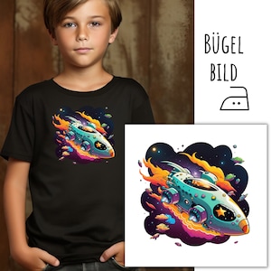 May include: A black t-shirt featuring a colourful illustration of a spaceship flying through space. The spaceship is surrounded by flames and stars. The text "BÜGEL BILD" is visible in the top right corner of the image.