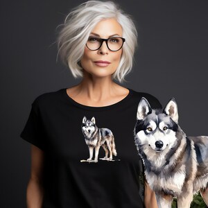 May include: A black t-shirt with a watercolor illustration of a wolf on the front. The wolf is gray and white with a black nose and eyes.