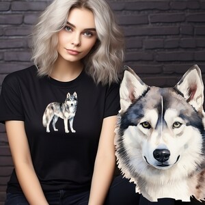 May include: A black t-shirt with a watercolor illustration of a grey and white husky dog. The dog is standing on all four legs and looking to the right. The woman wearing the shirt has blonde hair and is looking at the camera.