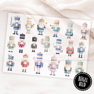 Könnte beinhalten: Ein Bogen mit bunten Nussknacker-Aufklebern in verschiedenen Designs. Jeder Aufkleber zeigt einen anderen Nussknackersoldaten, gekleidet in Blau-, Rot-, Rosa- und Grüntönen, mit goldenen Kronen und Accessoires. Die Aufkleber sind auf einem weißen Hintergrund angeordnet.