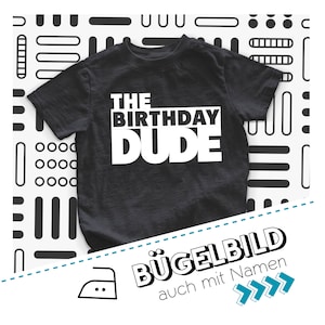 Peut inclure: T-shirt noir avec du texte blanc qui dit "THE BIRTHDAY DUDE". Le t-shirt est sur un fond blanc avec un motif géométrique noir et blanc. Le texte "BÜGELBILD auch mit Namen" est en bas de l'image.