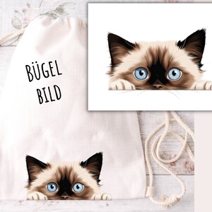 Könnte beinhalten: Eine weiße Kordeltasche mit dem Aufdruck "BÜGEL BILD" auf der Vorderseite. Ein süßes, cartoonartiges siamesisches Kätzchen mit blauen Augen schaut über den Rand der Tasche.