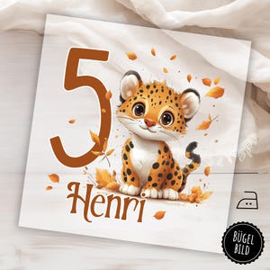 Op de afbeelding: Vierkante print met een cartoon luipaardjong, het nummer 5 en de naam "Henri" in bruin. Het jong heeft oranje en zwarte vlekken, met herfstbladeren verspreid. De achtergrond is wit.