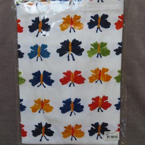 May include: White fabric with a repeating pattern of colorful butterflies in shades of blue, orange, red, and green. The butterflies have a simple, stylized design. The fabric is packaged in a clear plastic bag.