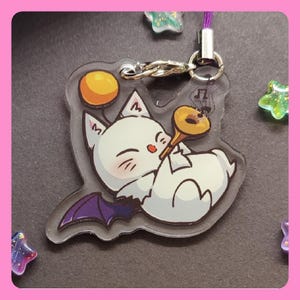Könnte beinhalten: Ein weißer und lilafarbener Charakter mit einem gelben Stern auf dem Kopf spielt Trompete. Der Charakter ist ein Anhänger an einem durchsichtigen Acryl-Schlüsselanhänger.