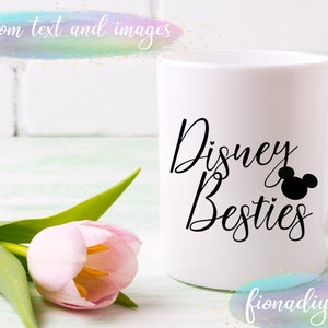 Pu&ograve; includere: Una tazza in ceramica bianca con testo nero che recita "Disney Besties" e una silhouette nera della testa di Topolino. La tazza &egrave; su una superficie di legno bianco con un tulipano rosa.