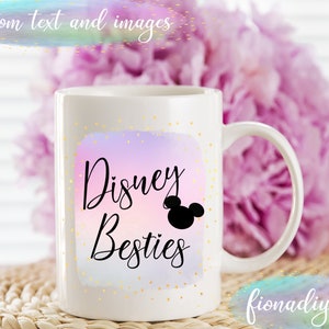May include: White ceramic mug with the text "Disney Besties" in black script, featuring a Mickey Mouse silhouette. The design is set against a pastel watercolor background with gold speckles. The mug has a curved handle.