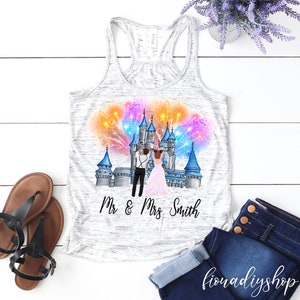 May include: A white tank top with a graphic of a couple in front of a castle with fireworks. The text "Mr & Mrs Smith" is printed below the graphic.
