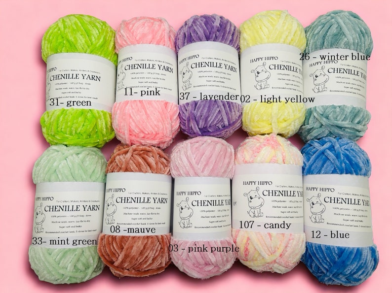 Op de afbeelding: Assortiment van chenille garenklossen in verschillende kleuren, waaronder groen, roze, lavendel, geel, mintgroen, mauve, roze paars, snoep en blauw. Elke klos heeft een label met het Happy Hippo-logo en de kleurnaam.