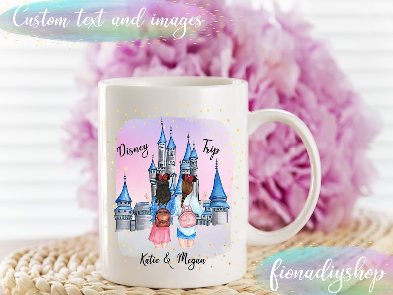 Pu&ograve; includere: Tazza in ceramica bianca con un'illustrazione colorata del castello di Cenerentola e due donne di fronte. Il testo "Disney Trip" &egrave; sopra il castello e "Katie & Megan" &egrave; sotto.