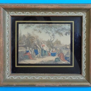 May include: A framed antique print depicting a group of people in a rural setting. The print is in a wooden frame with a gold-colored border. The print features a group of people in a rural setting, with a tree in the background. The print is in a wooden frame with a gold-colored border.